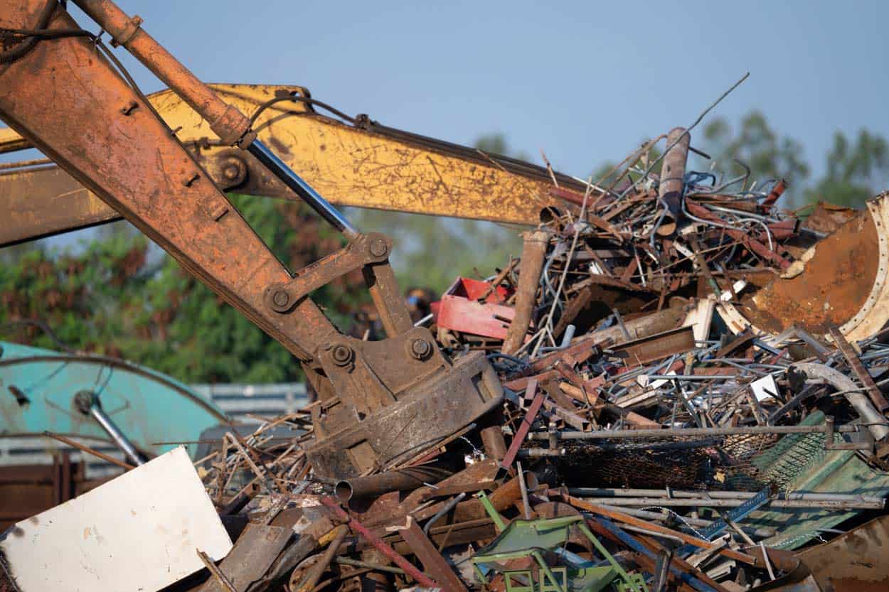 excavator magnet lifting steel scraps from recycling pile