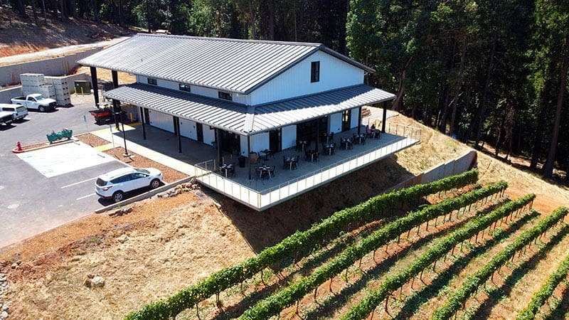 Custom agricultural steel building with open clear-span interior, large equipment, and hay bales inside, located on a Northern California farm.
